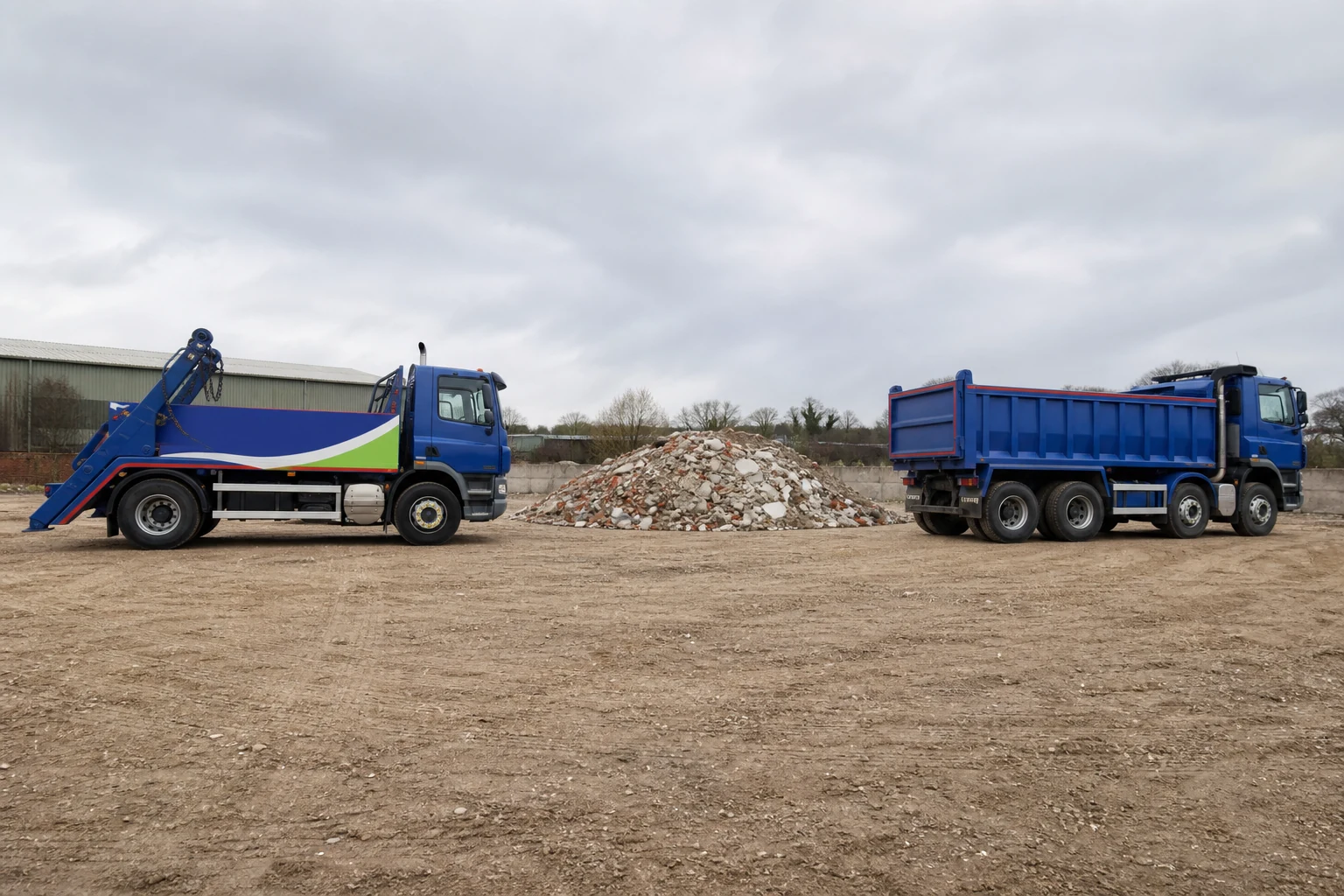 Grab lorry and tipper lorry positioned near a rubble pile.
